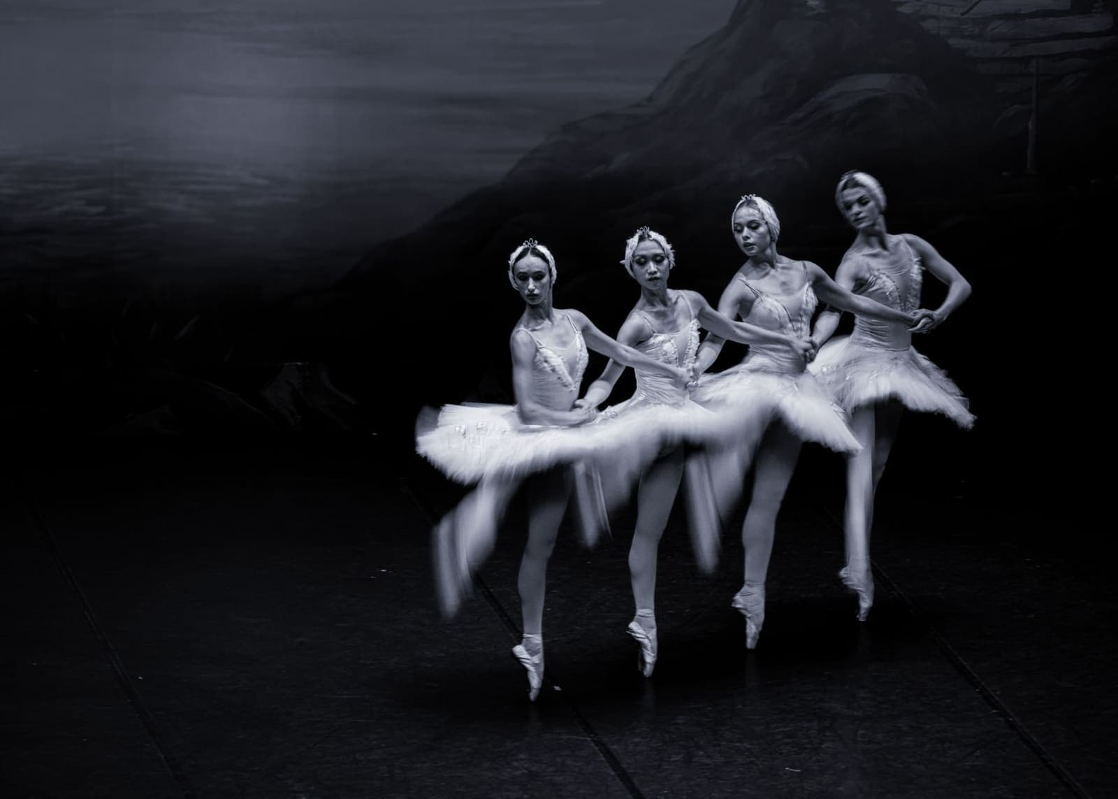 Ballet dancers performing on a theatrical stage with dramatic lighting