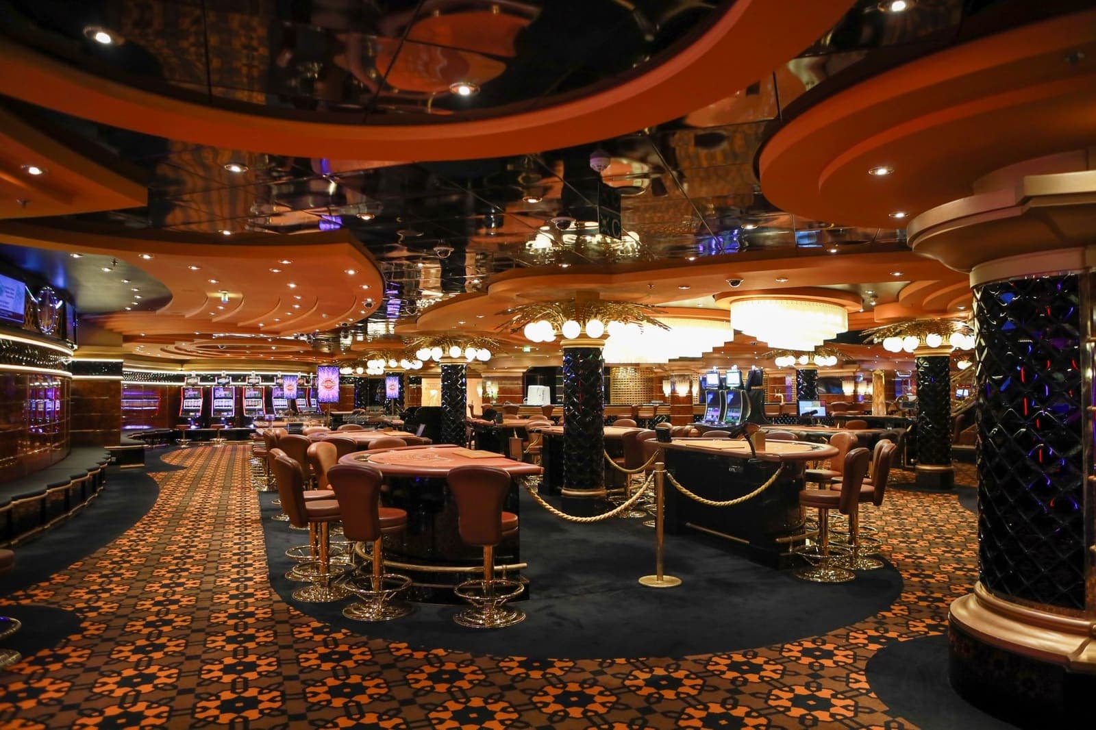 Row of brightly lit slot machines on a casino floor with jackpot displays