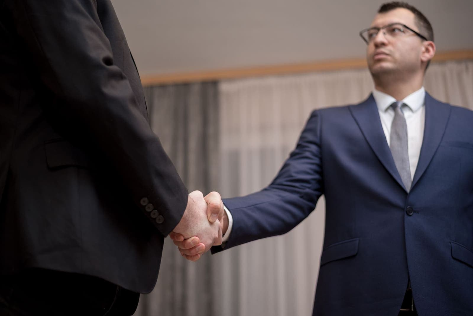 Two business executives shaking hands in a modern office setting