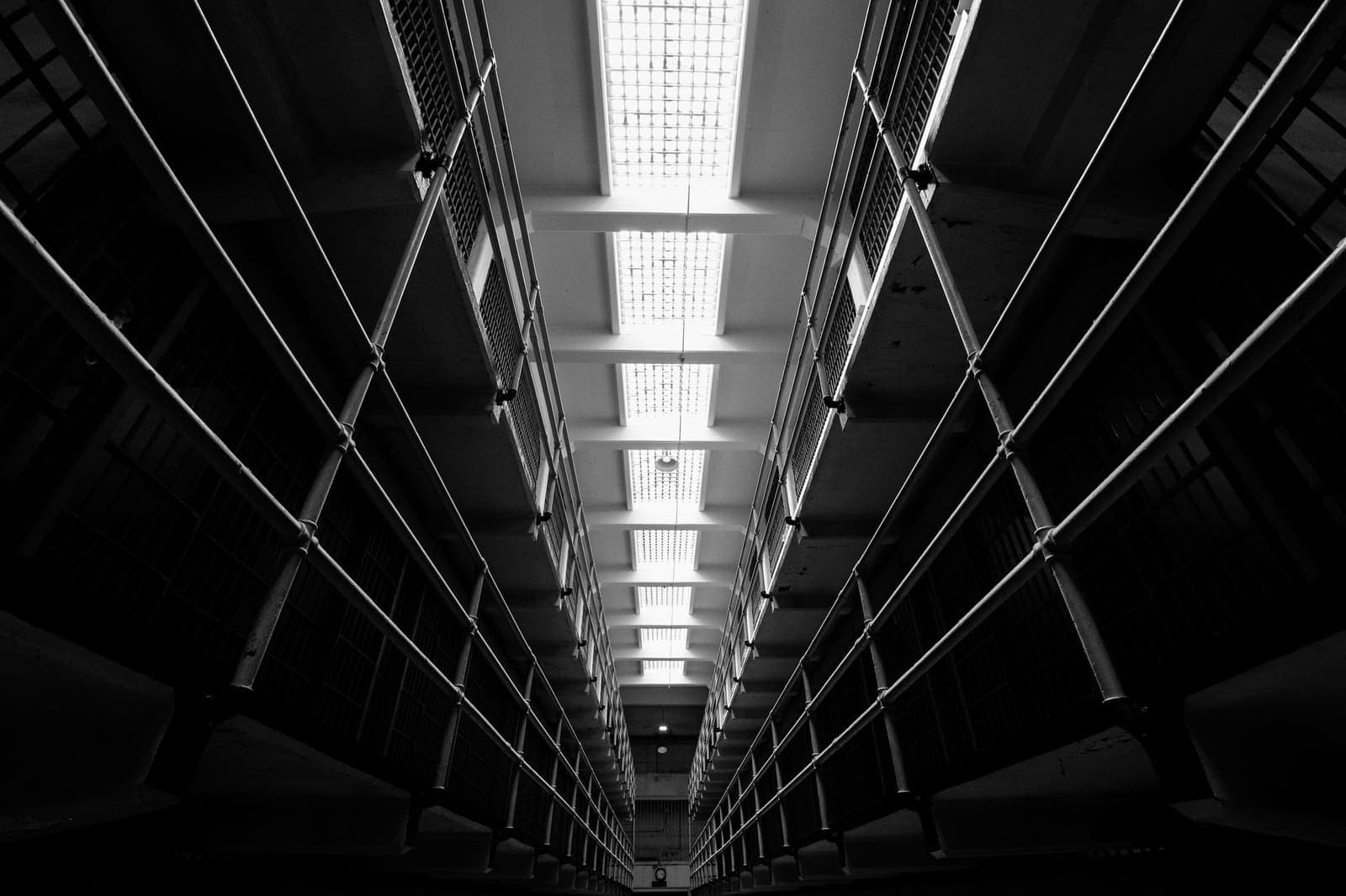 Dimly lit jail corridor with rows of cell bars